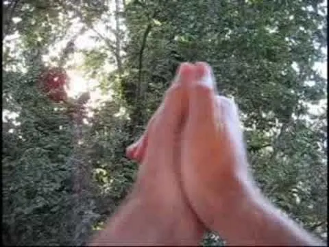 Hand holding a red craft stick above craft supplies, including scissors and glue.