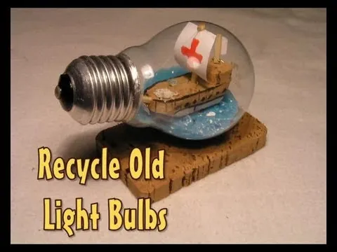 Light bulb sculpture with a miniature ship inside and a sign that reads "Recycle Old Light Bulbs."