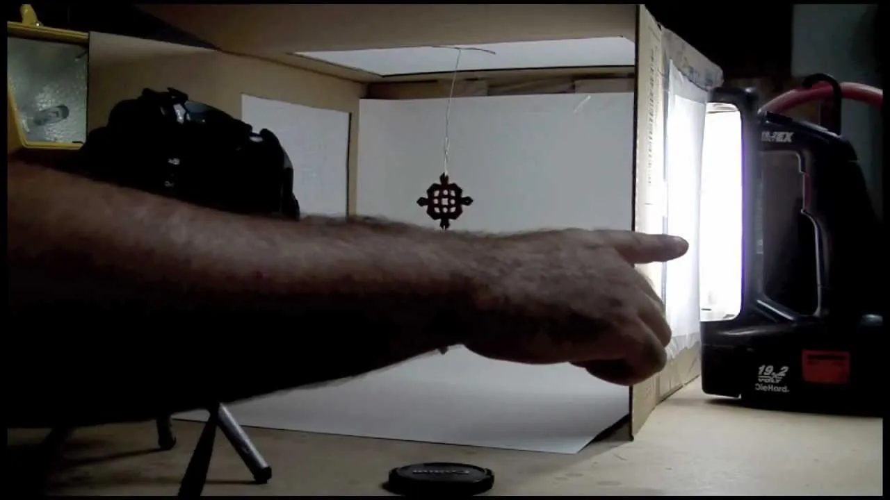 Hand pointing towards a light source in a photography setup.