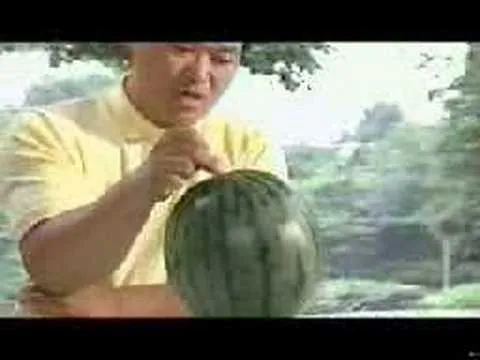 A person carving a watermelon outdoors.