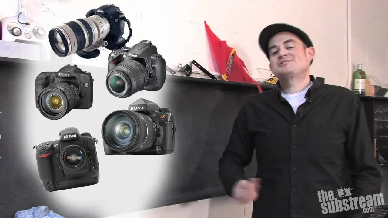 Man standing with a display of various cameras in the background.