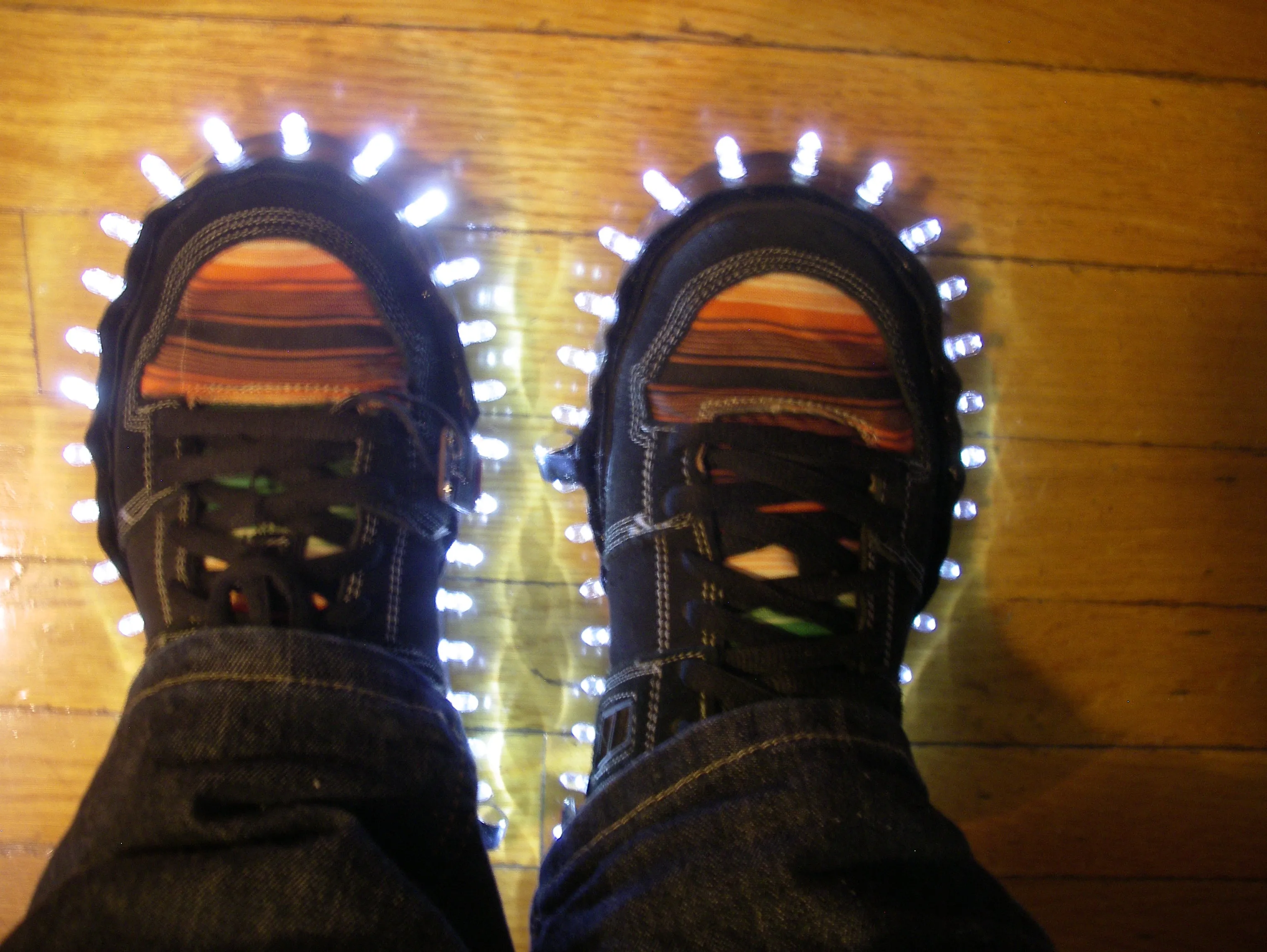 LED sneakers with illuminated soles on wooden floor.