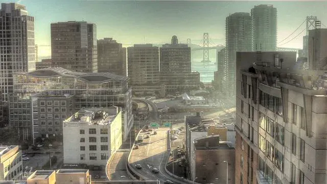 City skyline with buildings and a bridge in the background.