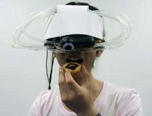 A person wearing a head-mounted display while holding a donut.