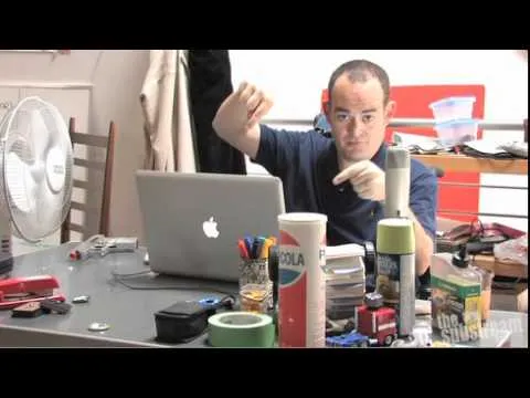 Person working at a desk with various tools and a laptop.