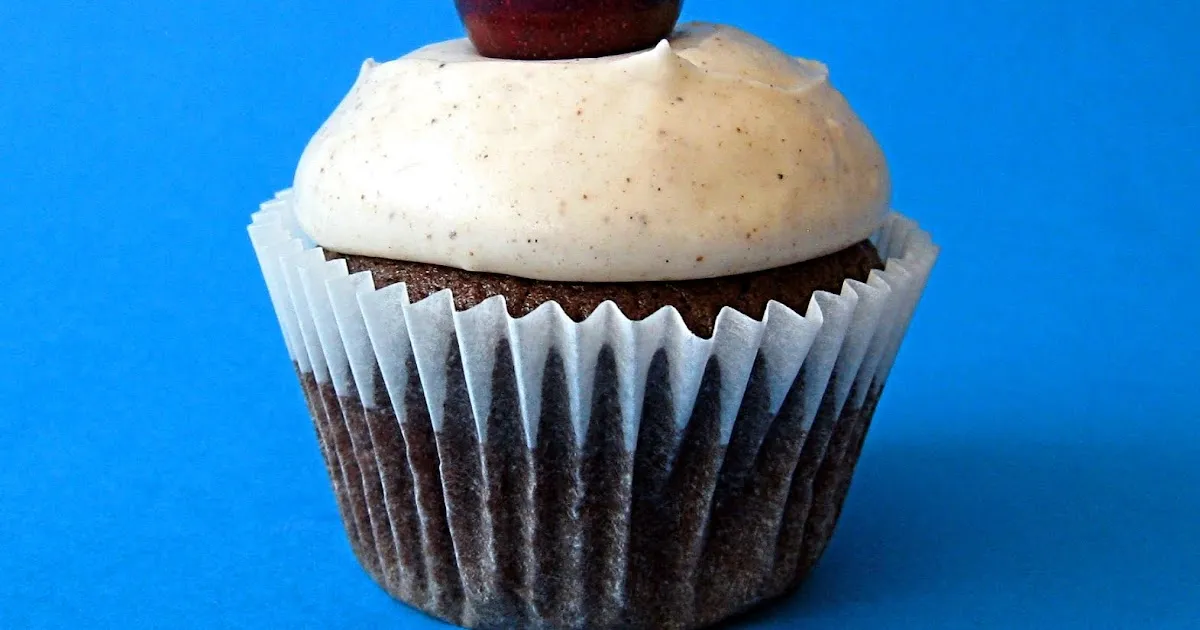 Chocolate cupcake with vanilla frosting and a cherry on top.