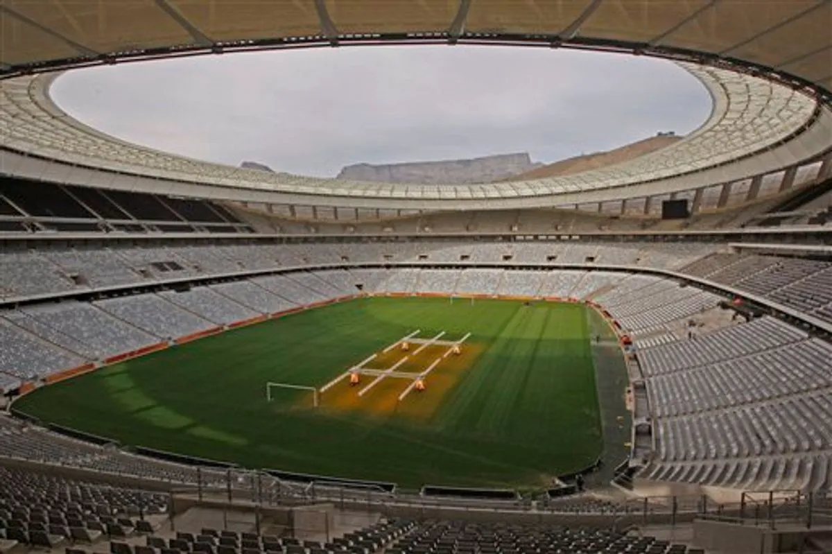Empty sports stadium with a green field and seating areas.