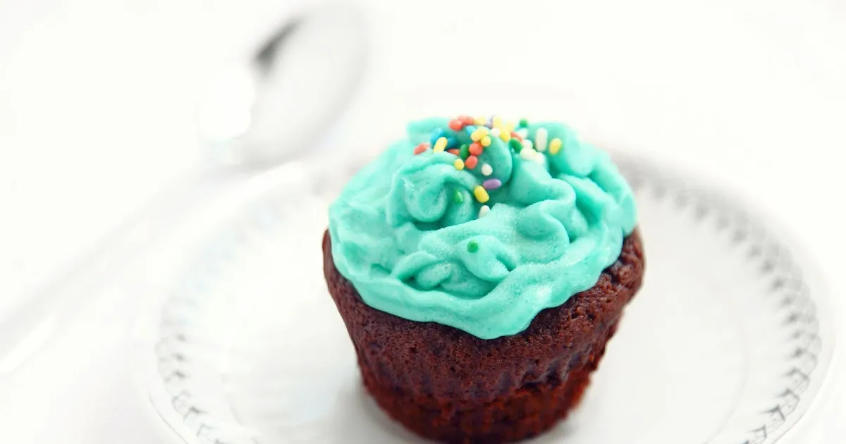 Chocolate cupcake with turquoise frosting and colorful sprinkles.