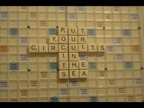 Scrabble tiles spelling "Put Your Circuits In The Sea" on a game board.