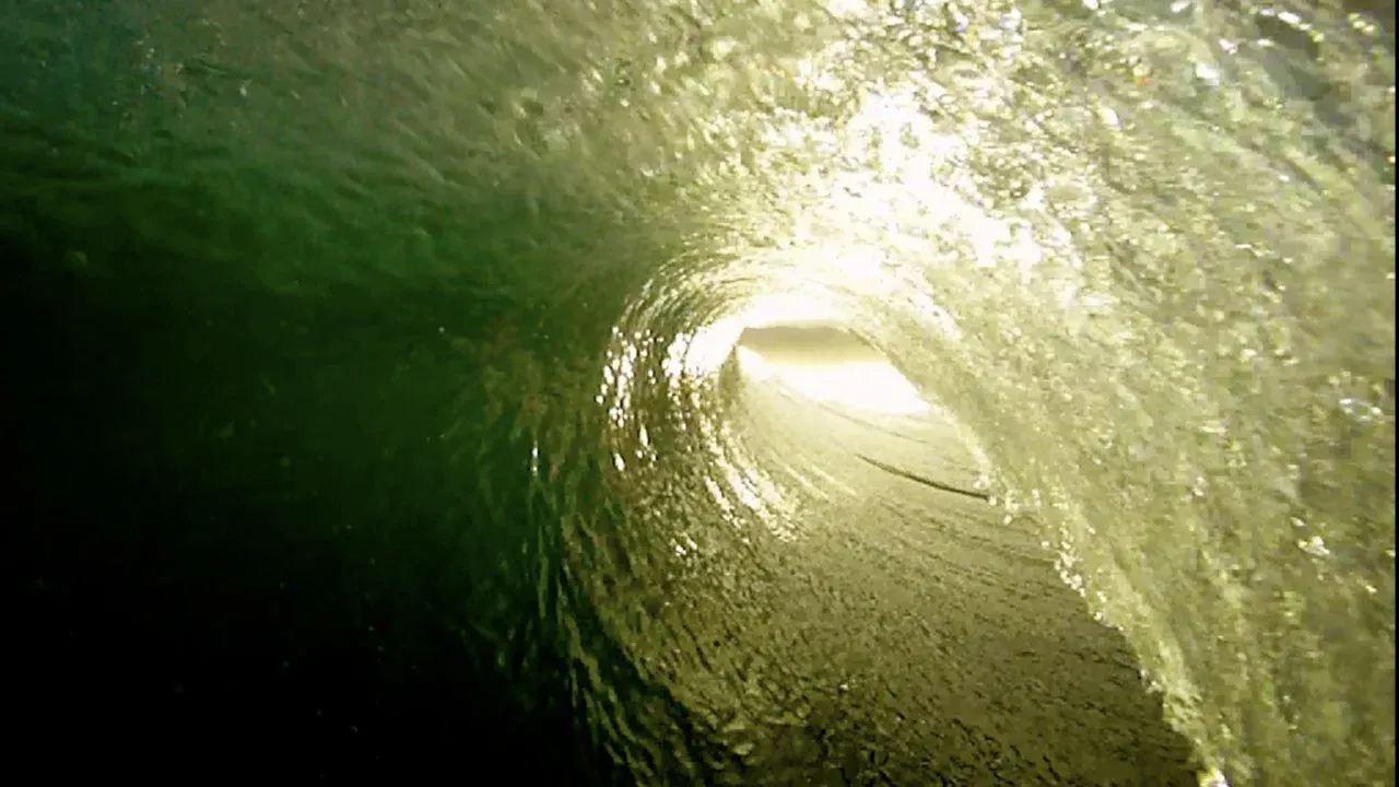 Aerial view of a breaking wave forming a tunnel.