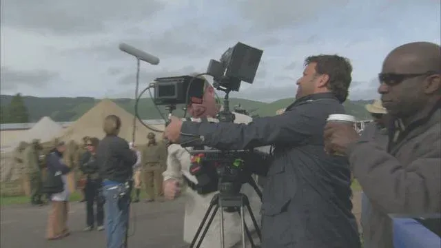 Videographer filming an outdoor scene with a professional camera.