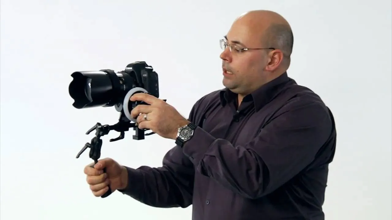 Man holding a DSLR camera on a stabilizing rig.