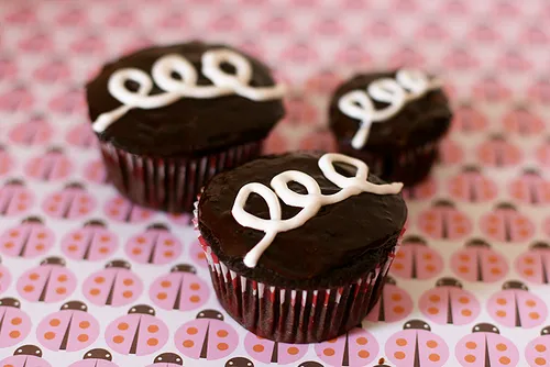 Chocolate cupcakes with white icing swirls on top.