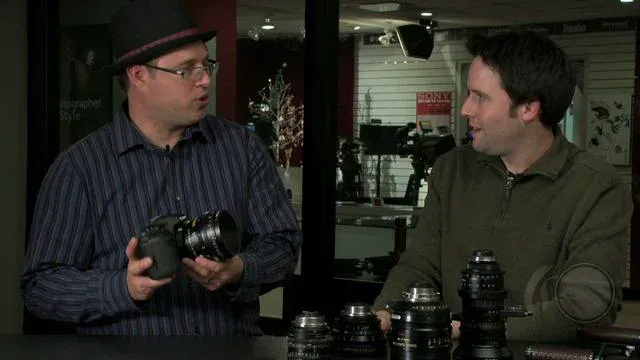Two men discussing photography equipment, one holding a camera and another listening intently.