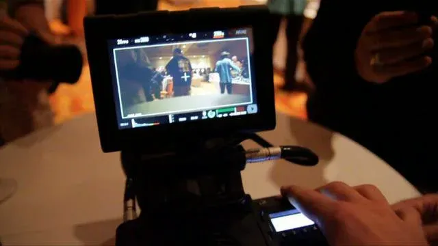 Camera monitor displaying video footage of a scene with people.