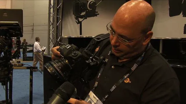 A photographer adjusting settings on a professional camera at a trade show.