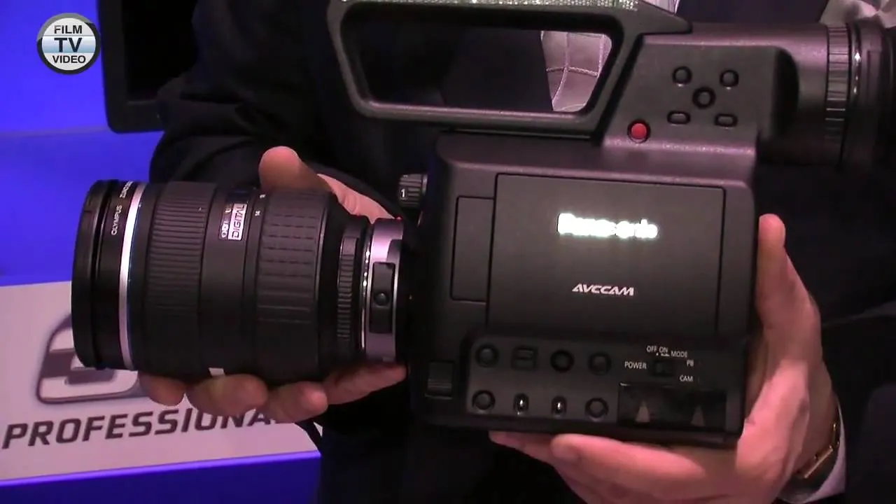 Professional camcorder with interchangeable lens held by a person.
