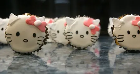Hello Kitty-themed macarons arranged on a reflective surface.