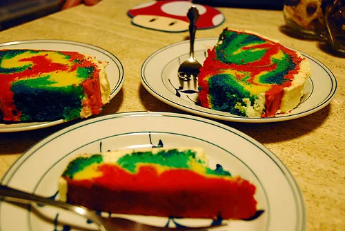 Colorful rainbow cake slices on white plates with forks.