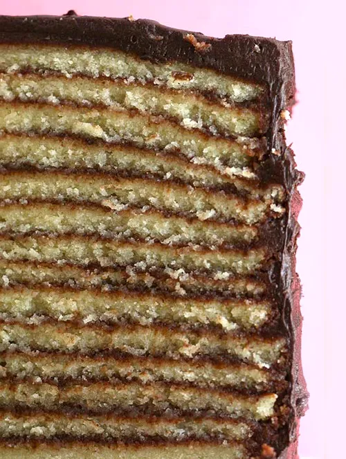 Layered chocolate cake with a pink background.