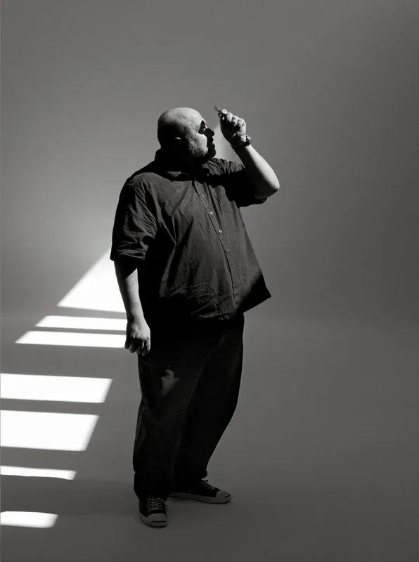 A contemplative man standing in a beam of light.