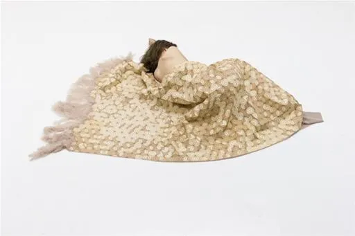 A person lying under a patterned blanket.