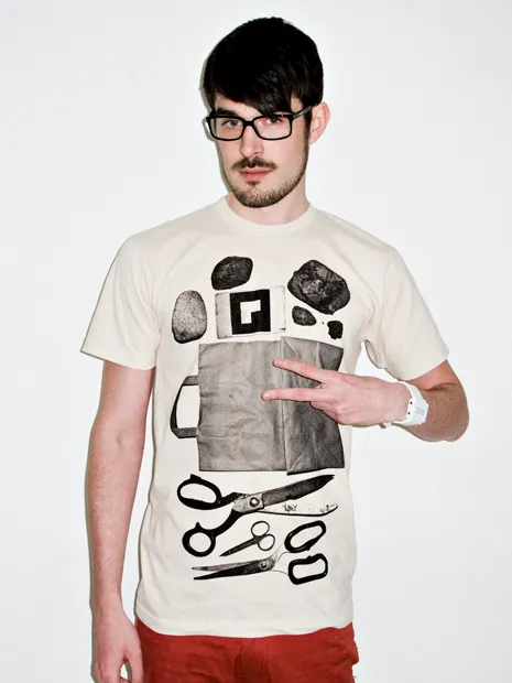 Young man wearing a graphic T-shirt with various illustrations, posing with a peace sign.