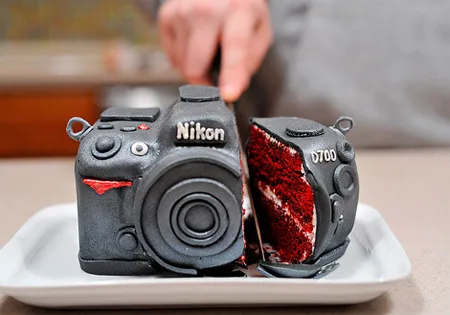 Camera-shaped cake being cut, revealing red velvet interior.