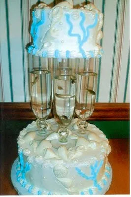 Three-tiered wedding cake with blue accents and decorative champagne flutes.