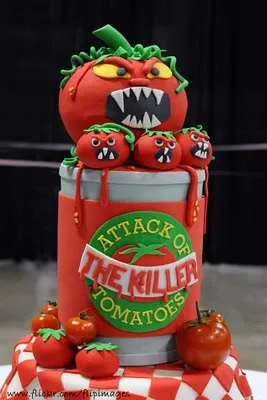 Eerie cake design featuring a tomato monster atop a can with playful tomato figures.