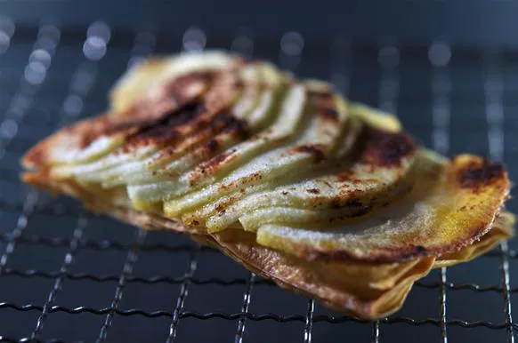 Baked potato chips with thinly sliced apples on a wire rack.