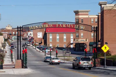 Historic Farmville entrance with festive decorations and vehicles on the street.
