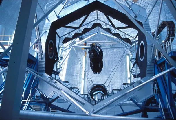 Observatory interior with large telescope and structural framework.