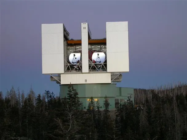 Large astronomical observatory with dual telescopes against a twilight sky.