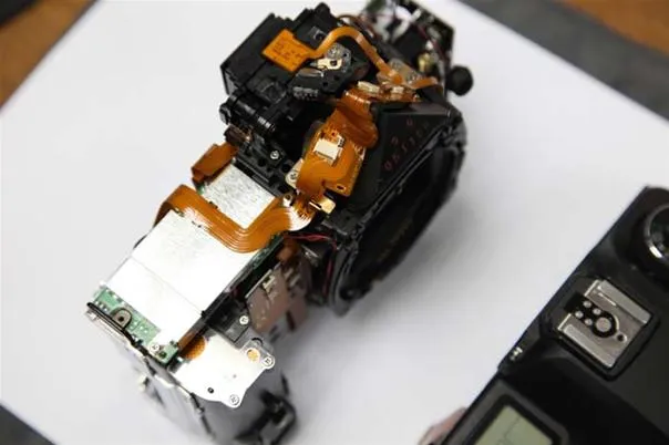 Camera mechanism disassembled on a white surface.