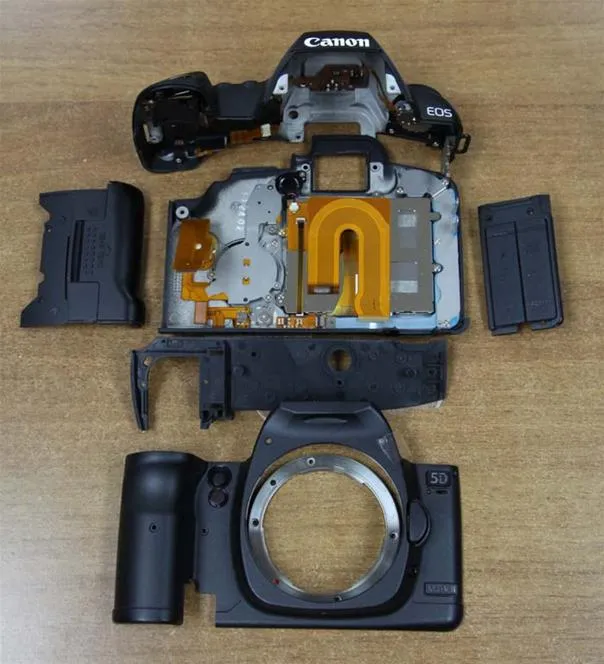 Disassembled digital camera components on a wooden surface.