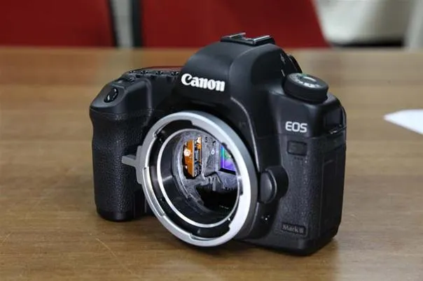 Canon EOS DSLR camera on a wooden surface.
