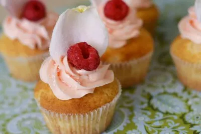 Pink frosted cupcakes with raspberries and edible flowers.