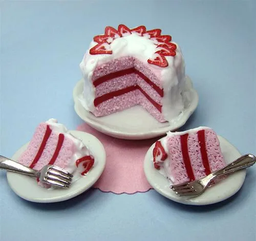 A slice of pink striped cake with whipped cream and strawberries on a plate, accompanied by two forks.