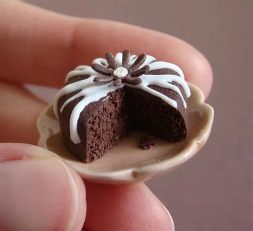 Miniature chocolate cake with white frosting and a slice cut out.