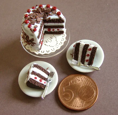 Miniature chocolate cake slices on plates with a coin for scale.