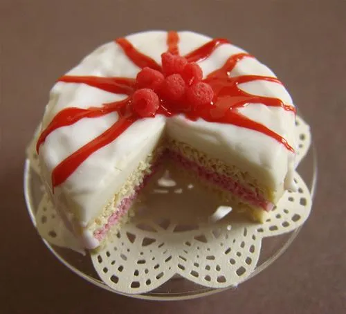 Strawberry-topped cake on a decorative plate with a slice removed.