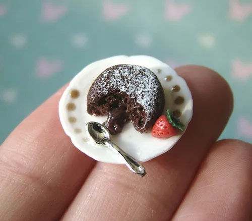 Miniature dessert on a plate with a spoon and a strawberry.