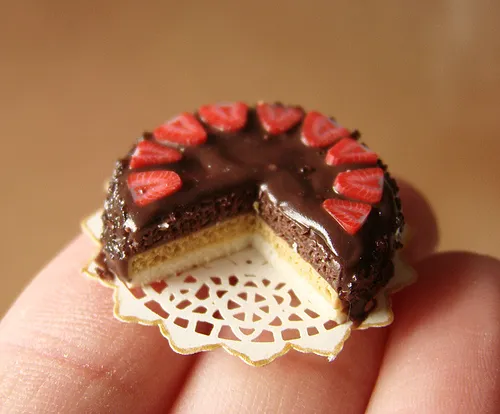 Miniature chocolate cake with strawberries on a lace doily.