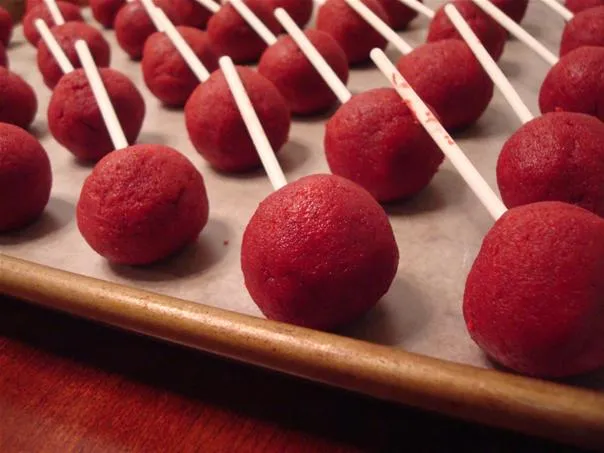 Red velvet cake pops on a baking tray.
