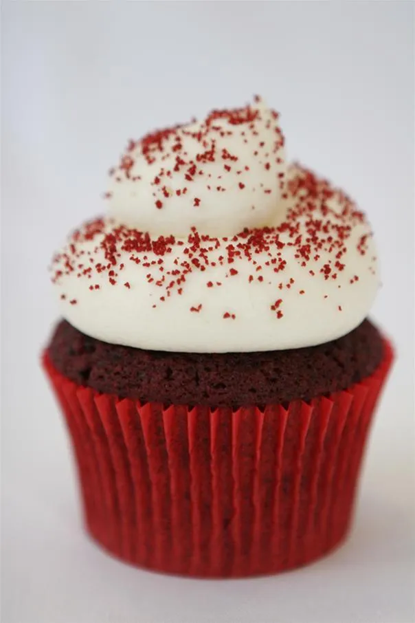 Red velvet cupcake with cream cheese frosting and red sprinkles.