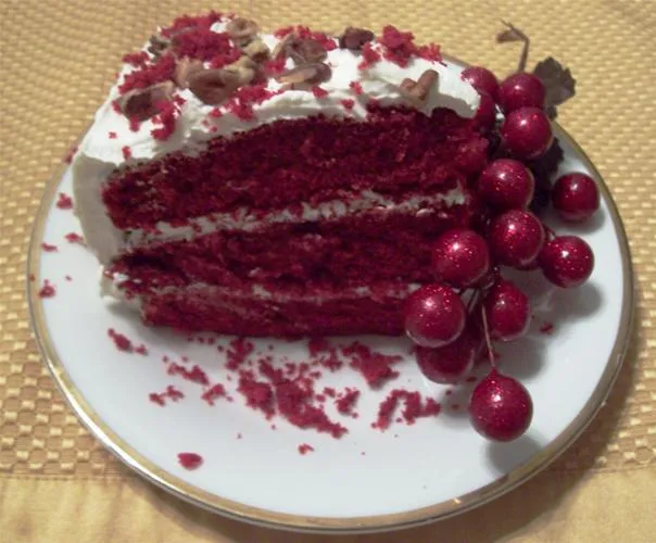 Red velvet cake slice with whipped cream and cherries on a plate.