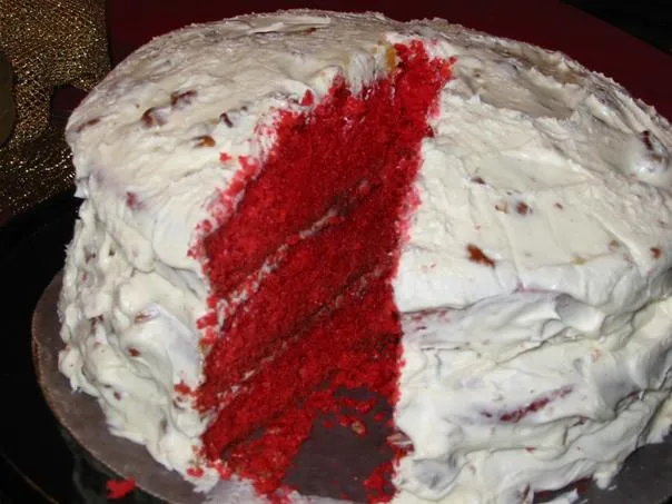 Red velvet cake with cream cheese frosting and a slice cut out.