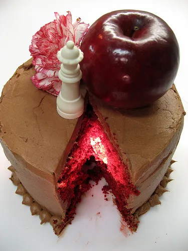 Chocolate cake with red filling and a decorative red apple on top.