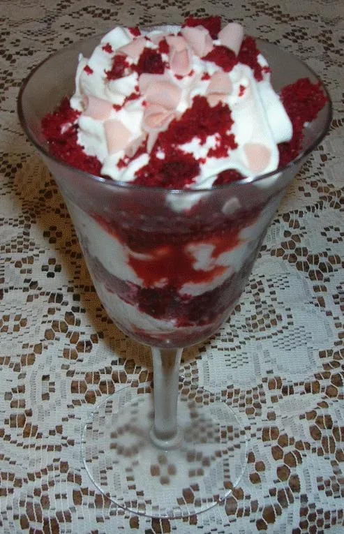 Dessert parfait with layers of raspberry and whipped cream in a glass.